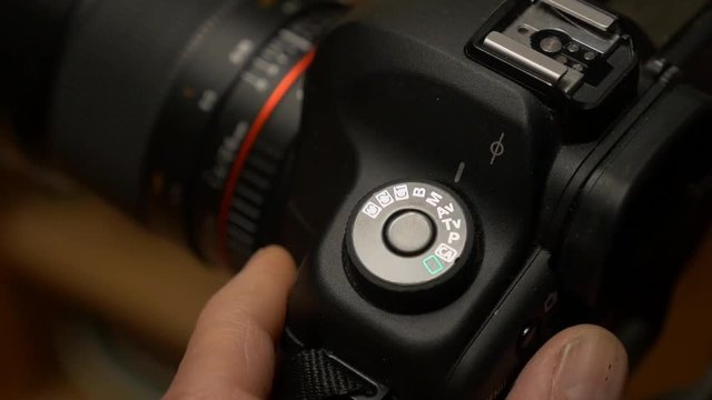 Photographer changing settings on a digital camera from automatic to manual