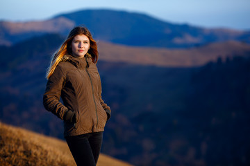 Young woman hiker hiking on mountain trail. Travel concept with space for text. Happy traveler standing on top of a mountain and enjoying sunset view
