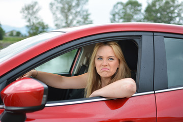 Fototapeta na wymiar Young blonde girl in red car mocking at somebody