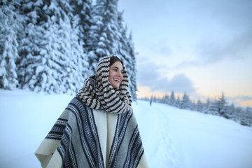 Young woman winter portrait. Happy young woman walking in winter forest. Happy girl having fun in the snow. Snow covered trees in the winter sun light. Snowy pine trees on a winter landscape