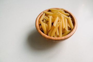 Dried rigatoni pasta in wooden bowl