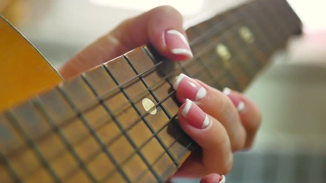 woman's hands playing acoustic guitar, close up