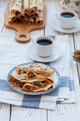 Thin pancakes for breakfast. Maslenitsa. On the table, a dish with pancakes, coffee and jam from feijoa