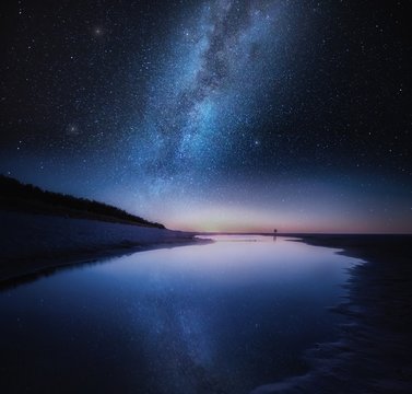 Sea shore in night with stars reflected in water