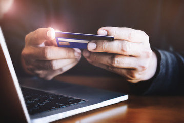 Online payment,Man's hands holding credit card and using laptop computer for online shopping.