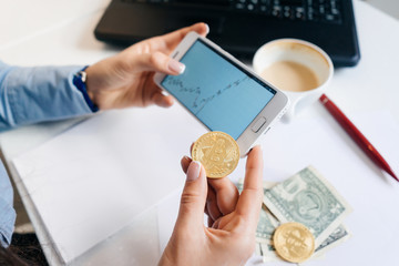 a woman holds a crypto-currency on the background of graphs