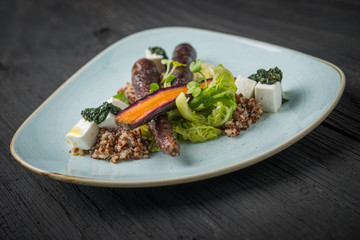 Vegan dish in plate on rustic wooden table, purple carrot with kinoa