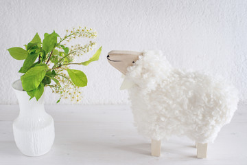 Lamm und Vase mit Blüten, Traubenkirsche blüht im Frühling