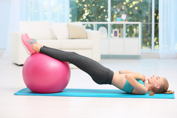 Young woman in sportswear doing exercises indoors