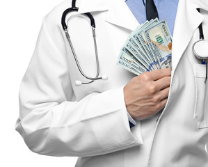 Doctor putting money in pocket on white background, closeup. Corruption concept