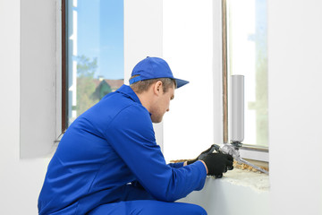 Construction worker repairing window in house