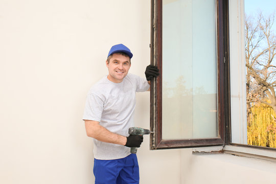 Construction worker repairing window in house