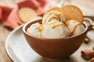 Bowl of ice cream with caramel sauce and cookies on table