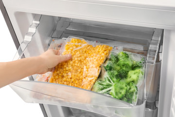 Woman taking frozen vegetables from refrigerator, closeup