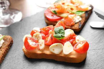 Tasty bruschetta with cherry tomatoes and mozzarella on slate plate