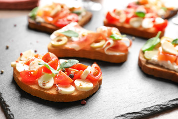 Tasty bruschetta with cherry tomatoes and mozzarella on slate plate