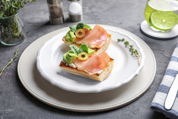 Tasty bruschettas with avocado and prosciutto on plate