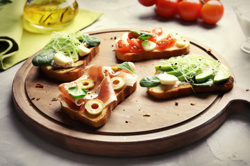 Wooden board with tasty bruschettas on table