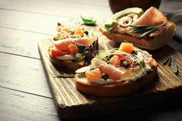 Wooden board with tasty bruschettas on table