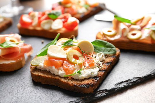 Tasty bruschetta with olives and salmon on slate plate