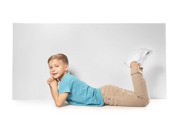 Cute boy with blank advertising board on white background