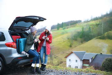 Obraz premium Female tourists near car in countryside