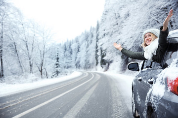 Happy tourist enjoying the beauty of snowy landscape while travelling by car