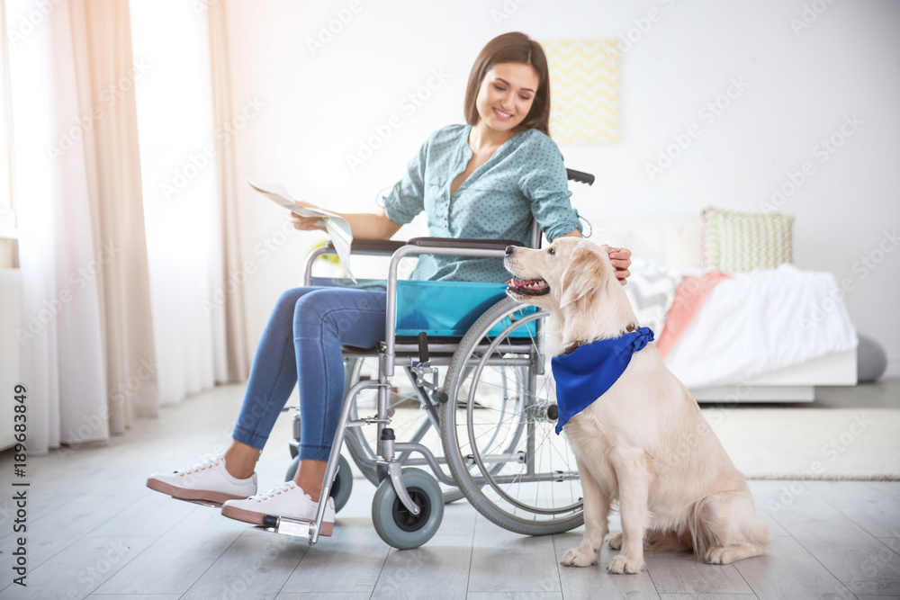 Canvas Prints Woman in wheelchair reading newspaper with service dog by her side indoors