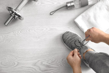 Man tying shoe laces in gym, top view