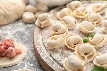 Raw meat dumplings on wooden board, closeup