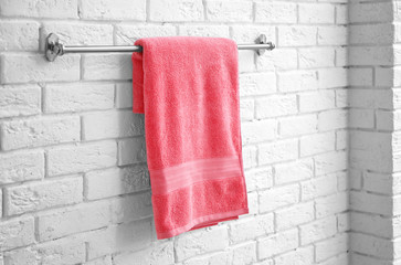 Rack with clean soft towel on brick wall