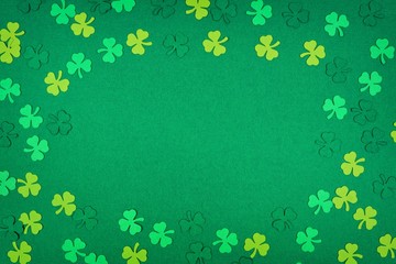 St Patricks Day frame of paper shamrocks over a green textured background