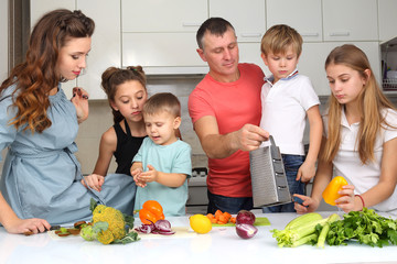 family with children cut vegetables for cooking