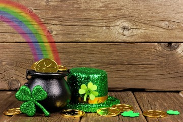 St Patricks Day Pot of Gold with rainbow, shamrocks and hat against rustic wood