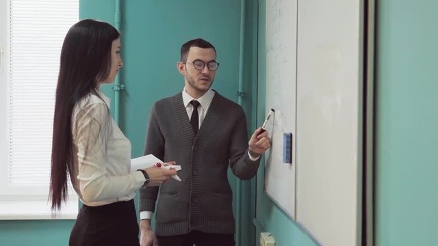 Man and woman conduct a business meeting near whiteboard