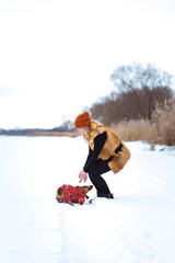 beautiful girl in a fur vest plays with a dog in the snow