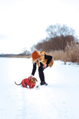 beautiful girl in a fur vest plays with a dog in the snow