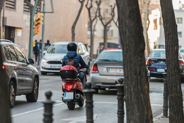 Red motorcycle woman drive in the streets of Spain making deliveries
