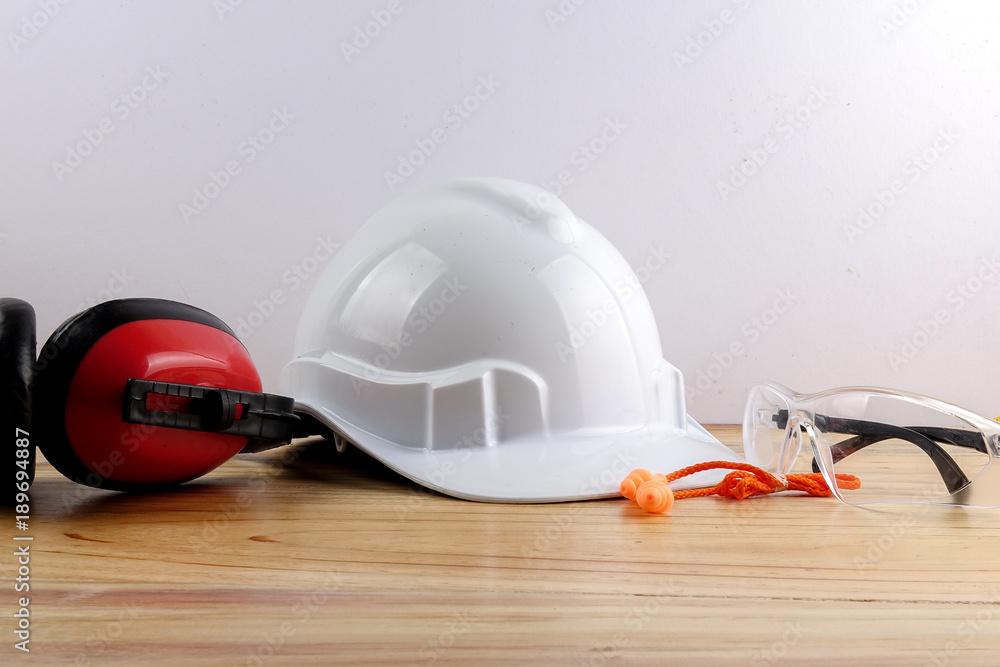 Wall mural HEALTH AND SAFETY CONCEPT. Personal protective equipment on wooden table over white background.