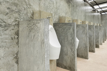 White Urinal Men in Men Public Toilet with Concrete Wall Loft Style Wide Angle
