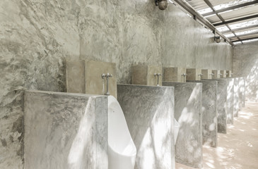 White Urinal Men in Men Public Toilet with Concrete Wall Loft Style