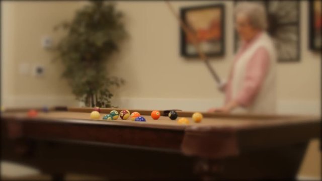 A dolly shot of playing pool lady playing pool in retirement home
