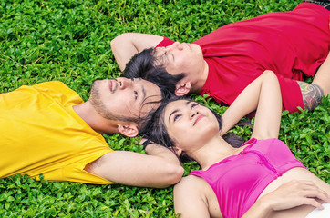 Love triangle, One girls and two guy lying on the grass.