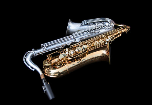 Full view of two saxophones lying down isolated in black