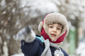 Fototapeta premium Young boy with fur hat playing with snow