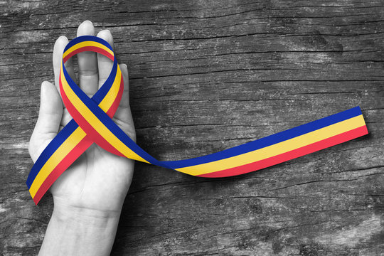 Red Yellow Blue Trisomy Awareness Month ribbon in March on helping hand on grunge aged background (clipping path)