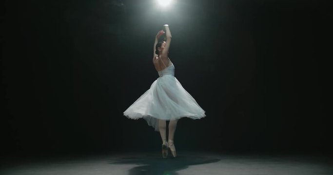 4K video footage closeup of a beautiful female ballet dancer on black background, slow motion