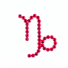 Capricorn. Sign of the zodiac of red rhinestones on a white background.