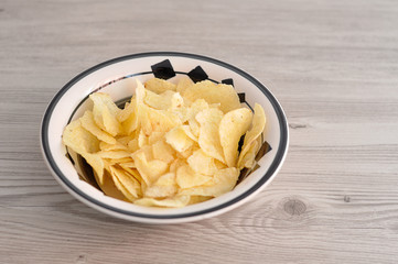 A bowl of crisps on a wooden table