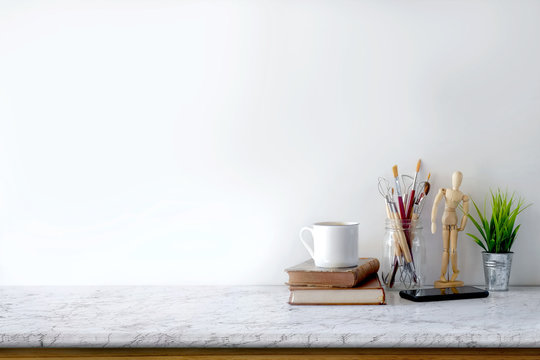 Front view of Artist or Designer desk with creative tools, vintage books and coffee mug . copy space for product display montage.